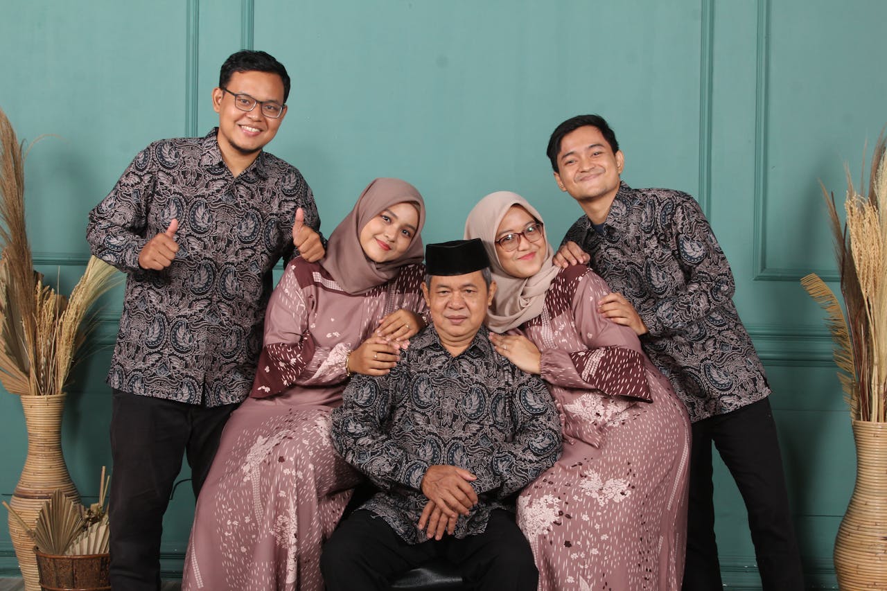 home-hero Family portrait featuring adults in coordinating traditional attire against a teal backdrop.