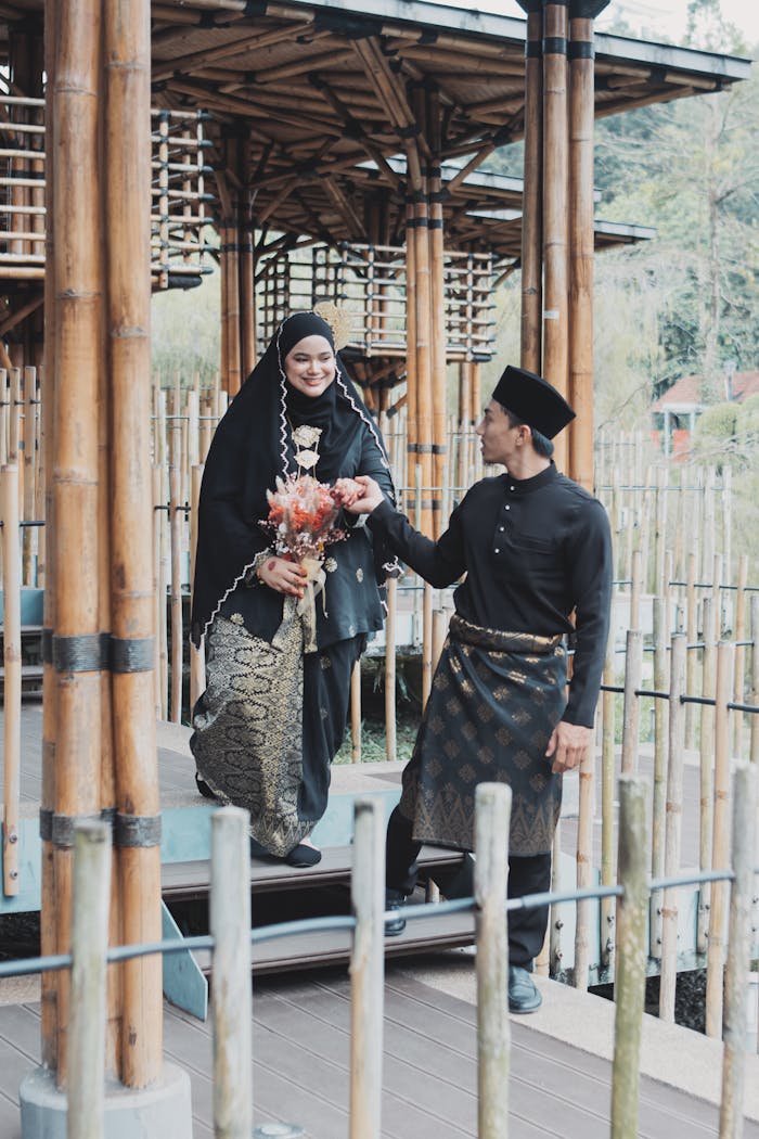 services-05 A smiling couple in traditional Malaysian clothing walking together outdoors.