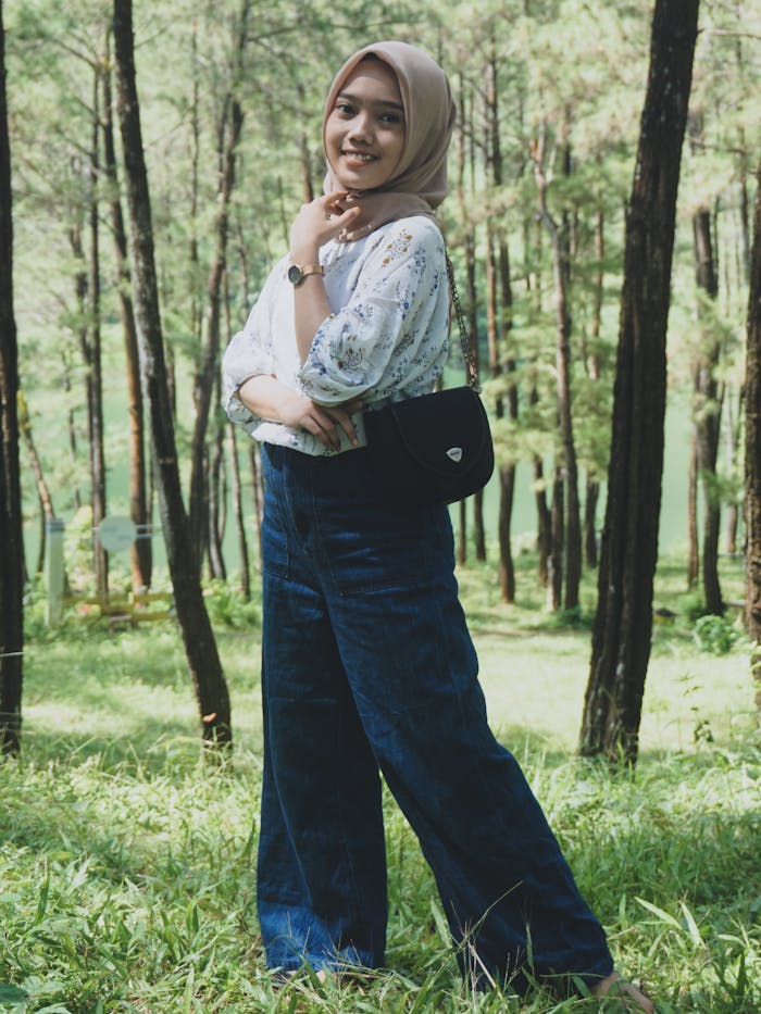 A young woman confidently poses in a serene Malaysian forest, exuding happiness and style.