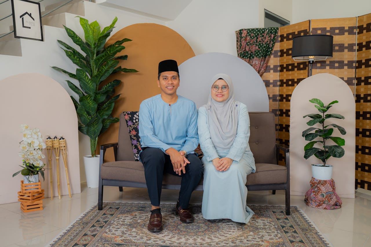 A couple in traditional attire sitting on a sofa in a beautifully decorated indoor setting.